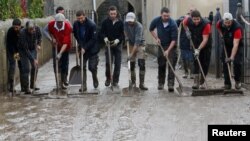 People use shovels and brooms to clean away mud as clean-up operations continue the day after some of the worst flash floods in a century turned rivers into raging torrents that engulfed homes and swept away cars hit the southwestern Aude district of Fran