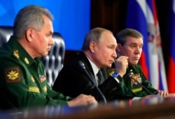 FILE - Russian President Vladimir Putin, center, gestures while meeting with Russian Defense Minister Sergei Shoigu, left, and Chief of General Staff of Russia Valery Gerasimov in the National Defense Control Center in Moscow, Russia, Dec. 24, 2019.
