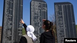 FILE - Kosovo Albanians read the names of the victims killed during the 1998-99 Kosovo war, as part of a ceremony marking the 18th anniversary of the massacre in the village of Izbica, March 28, 2017. 