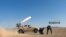 FILE - May 25, 2017 photo provided by the government-controlled Syrian Central Military Media, shows Syrian government troops firing multiple launcher rockets at insurgent group's position, in the Syrian province of Homs.