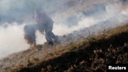 FILE - A farmer burns rice straw at his field in Qalyub, causing a "black cloud" of smoke that spreads across the Nile valley, near the agricultural road which leads to the capital city of Cairo, Egypt, Oct. 26, 2016. 