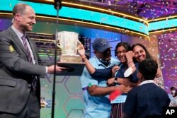 Harini Logan, 14, from San Antonio, Texas, celebrates winning the Scripps National Spelling Bee with her family, as Scripps CEO Adam Symson, left, presents the Scripps National Spelling Bee winning trophy Thursday, June 2, 2022, in Oxon Hill, Md. (AP Photo/Alex Brandon)