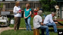 Familiares de un hombre asesinado, cuyo nombre no ha sido divulgado aún, reunidos en el patio de la casa, mientras la policía registra la vivienda, en Loveland, Colorado.