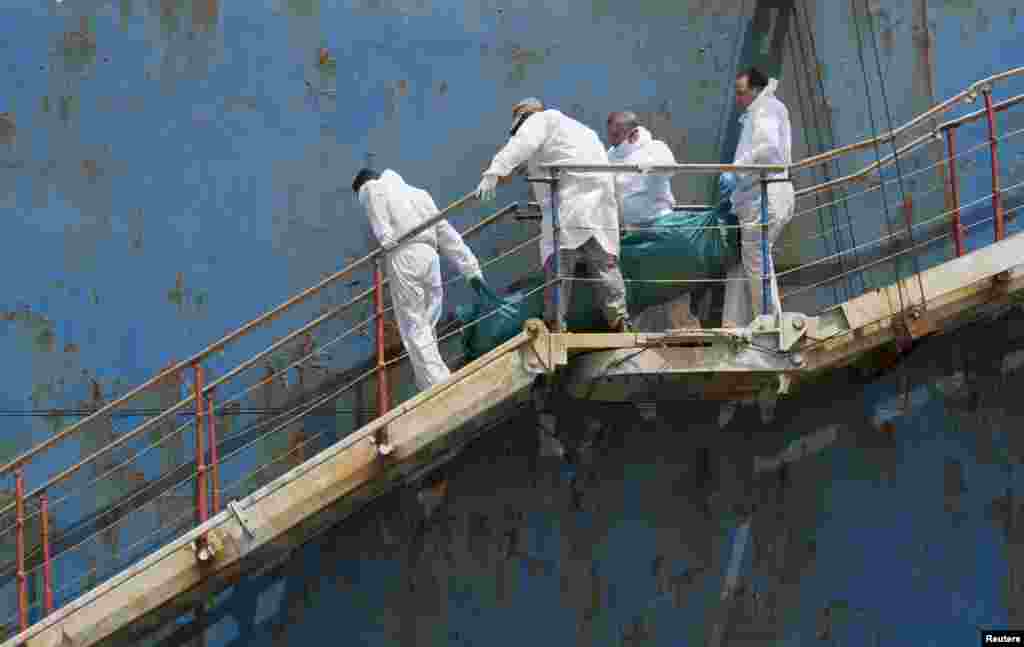 People carry the body of a dead migrant from a merchant ship as they arrive in the Sicilian harbor of Catania, southern Italy, May 5, 2015. &nbsp;