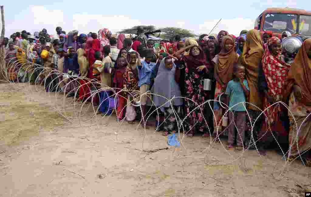 这是摩加迪沙的一个难民营。来自索马里南部的难民在铁丝网后面排队，领取援救物资。