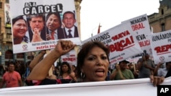 ARCHIVO - Una mujer participa en una marcha con un cartel de fondo que muestra imágenes de tres expresidentes peruanos, Alan García, Alejandro Toledo y Ollanta Humala, y de la candidata Keiko Fujimori con un mensaje que dice "A la cárcel". En Lima, el 16 de febrero de 2017.