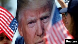 A supporter holds a portrait of former U.S President Donald Trump during a rally in Huntington Beach, California, a day after Trump was shot in an assassination attempt during a rally in Pennsylvania on July 13, 2024. (Etienne Laurent/Reuters)