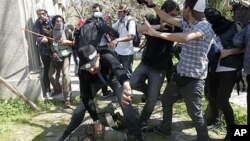 People try to help a riot policeman after he was hit by demonstrators during a protest marking the 1973 military coup in Santiago September 11, 2011.