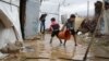 Hassan Fahd al Raja, holding a bucket, helps his siblings drain water out of their family's tent, which is part of a refugee camp in Lebanon's Bekaa valley. (Photo: John Owens for VOA) 