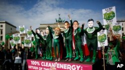 Des activistes de l’environnement en costumes verts portant des masques des dirigeants du G7 assistent à une manifestation devant la Porte de Brandebourg à Berlin, en Allemagne, le 15 mai 2015. (AP Photo/Markus Schreiber)