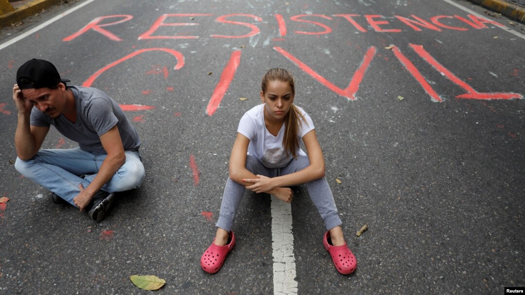 Opposition supporters sit next to graffiti on a street that reads "Civil resistance" during a protest against Venezuelan President Nicolas Maduro, in Caracas, Venezuela, May 2, 2017. 