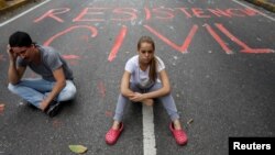 Opposition supporters sit next to graffiti on a street that reads "Civil resistance" during a protest against Venezuelan President Nicolas Maduro, in Caracas, Venezuela, May 2, 2017. 