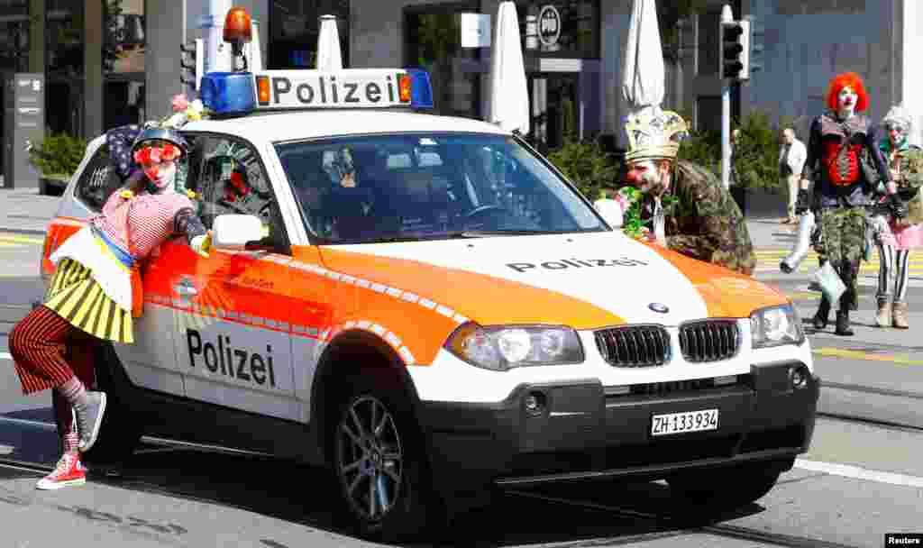 Protesters dressed as clowns stand next to a Swiss police car during a May Day demonstration in Zurich, Switzerland, May 1, 2019.