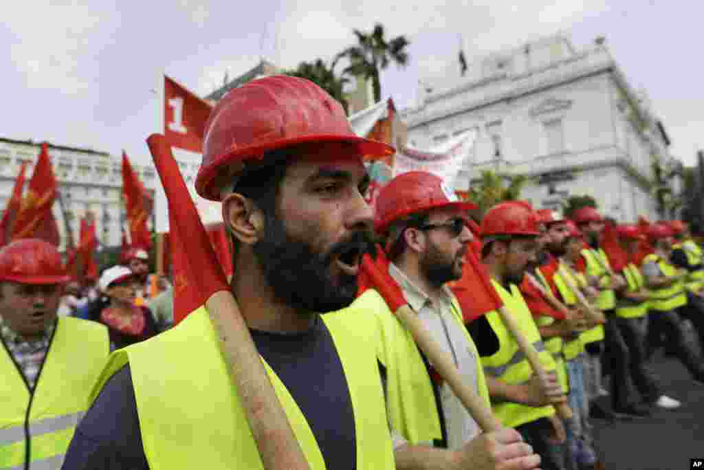 Demonstran yang mengenakan helm merah meneriakkan slogan-slogan saat ikut berdemo di luar gedung parlemen Yunani di Athena, Senin, 1 Mei 2017.