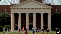 FILE - A group walks across the lawn on the campus of Wake Forest University in Winston-Salem, N.C., May 28, 2014. 