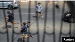 Pro-democracy protesters and a journalist run as riot police officers advance them during a rally against the military coup in Yangon, Myanmar, February 27, 2021. REUTERS/Stringer