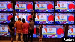 People watch Indian Prime Minister Narendra Modi address the nation amid concerns about the spread of COVID-19 on TV screens inside a showroom in Ahmedabad, March 19, 2020.