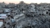 Palestinians walk among the rubble of buildings, amid a ceasefire between Israel and Hamas, in Khan Younis, in the southern Gaza Strip, Feb. 27, 2025.