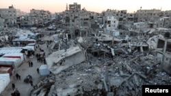 Palestinians walk among the rubble of buildings, amid a ceasefire between Israel and Hamas, in Khan Younis, in the southern Gaza Strip, Feb. 27, 2025.