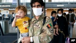 Families evacuated from Kabul, Afghanistan, walk through the terminal before boarding a bus after they arrived at Washington Dulles International Airport, in Chantilly, Va., on Friday, Aug. 27, 2021. (AP Photo/Jose Luis Magana)