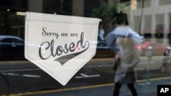 A woman walks along through the Financial District past the closed Homage Ltd. restaurant which is normally open for breakfast and lunch, in San Francisco, March 16, 2020.