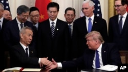 Tổng thống Donald Trump (ngồi, bên phải) bắt tay Phó thủ tướng Trung Quốc Lưu Hạc sau khi ký thoả thuận thương mại tại Nhà Trắng vào ngày 15/1/2020.
