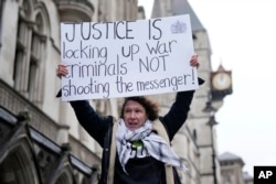 Žena nosi transparent sa porukom "Pravda je kada se zatvore ratni zločinci, a ne oni koji su nešto objavili" u Londonu, 21. februar 2024. (AP/Alastair Grant)