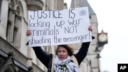 Žena nosi transparent sa porukom "Pravda je kada se zatvore ratni zločinci, a ne oni koji su nešto objavili" u Londonu, 21. februar 2024. (AP/Alastair Grant)