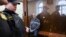 Founder of the Baring Vostok investment fund Michael Calvey (C) sits behind a cage glass window as he waits for the session in a court room in Moscow, Russia, Feb. 16, 2019.