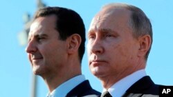 Tổng thống Nga Vladimir Putin, phải, và Tổng thống Syria Bashar Assad tại căn cứ không quân Hemeimeem ở Syria hôm 11/12. Nga bị các nhóm phiến quân ở Syria cáo buộc có âm mưu phá hỏng đàm phán hòa bình do LHQ điều giải. (Sputnik, Kremlin Pool Photo via AP)