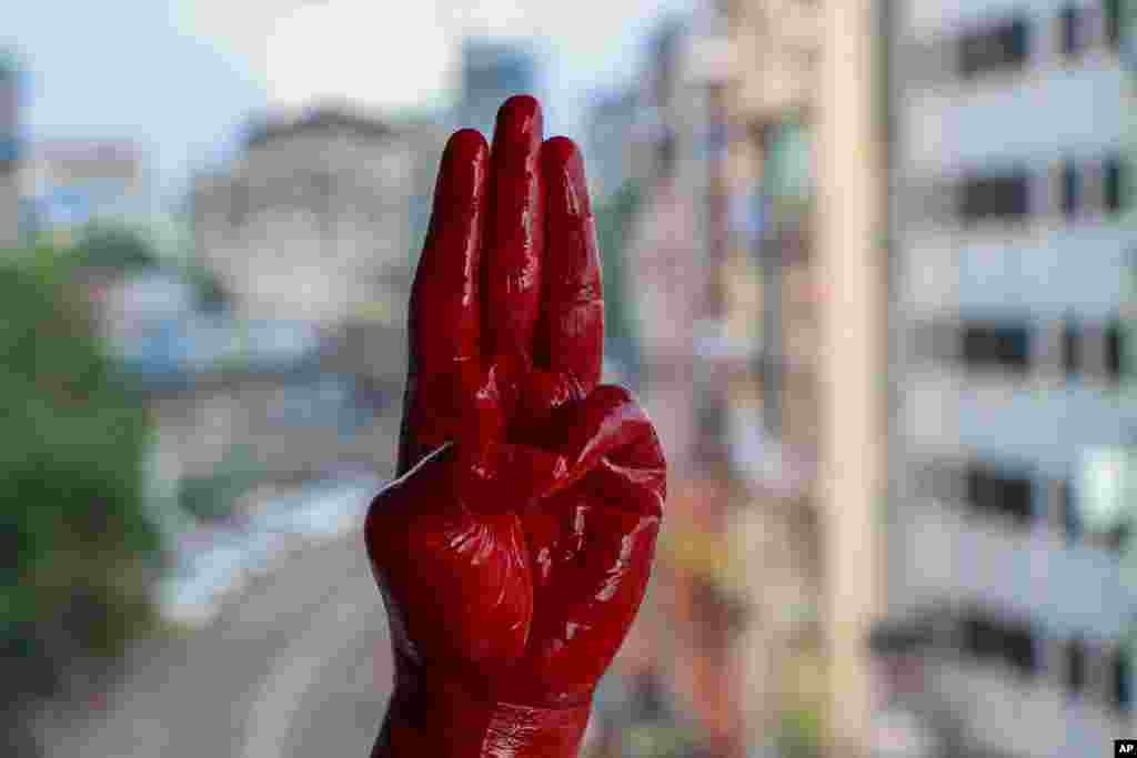 An anti-coup protester shows the three-fingered salute of resistance on his red-painted hand in memory of protesters who lost their lives, in Yangon, Myanmar.