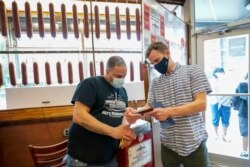 A Katz's Deli employee checks proof of vaccination for diners who will be eating inside the restaurant, Tuesday, Aug. 17, 2021, in New York. New York City is asking restaurants, gyms, museums and many other indoor venues to have patrons show proof…