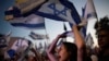 Orang-orang mengibarkan bendera Israel saat melakukan protes terhadap pemerintahan Perdana Menteri Israel Benjamin Netanyahu dan menuntut pemilihan umum di luar Knesset, parlemen Israel, di Yerusalem, Selasa, 18 Juni 2024. (Foto: AP)