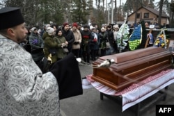 Familiares y amigos reaccionan mientras un clérigo oficia la ceremonia fúnebre de Yevgen Matveiev, alcalde de la ciudad de Dniprorudne en la región de Zaporizhia, en la ciudad de Bucha, región de Kiev, el 5 de diciembre de 2024, en medio de la invasión rusa de Ucrania.