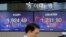 A currency trader walks near the screens showing the KOSPI left, and the foreign exchange rate between U.S. dollar in Seoul, South Korea, May 18, 2020. 