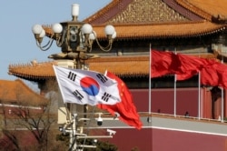FILE - South Korea and China's flags flutter next to Tiananmen Gate during the visit of South Korean President Moon Jae-In in Beijing, China, Dec. 15, 2017.