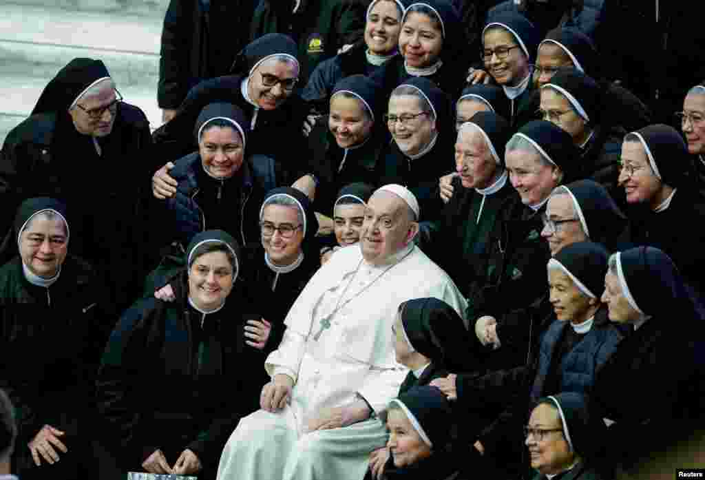 Pope Francis sits in between nuns, on the day of a weekly general audience, in Paul VI hall at the Vatican.