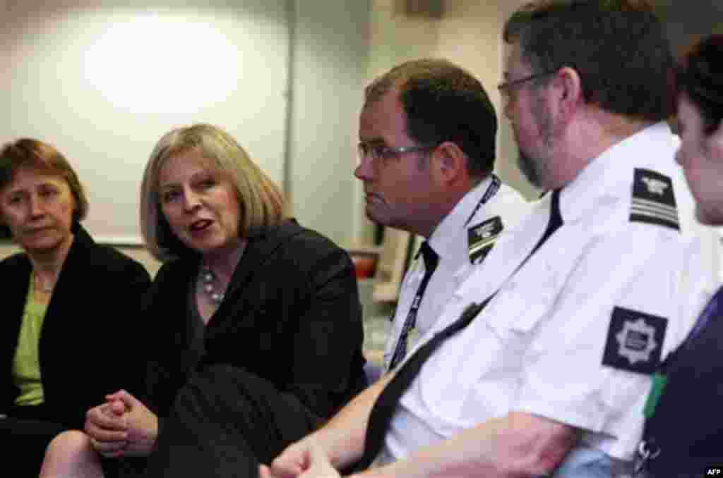 Home Secretary Theresa May, second left, visit the UK Border Agency staff at Terminal 5 of Heathrow Airport, London where they were shown differences between fake and real passports Tuesday Nov. 23, 2010. Britain's Home Office says it will be announcing t