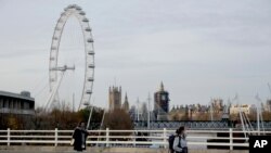 FILE - Women wear face coverings as they walk in London, Friday, Nov. 20, 2020.