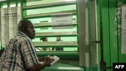 Um observador eleitoral observa enquanto os funcionários começam a contar os boletins de voto numa assembleia de voto em Libreville, a 16 de novembro de 2024.