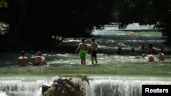 People swim in the Eisbach river that runs through the English Garden in Munich, Germany, June 26, 2019.