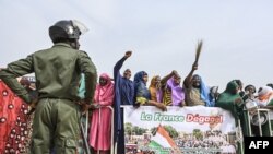 Nigerien National Police officers stand guard as supporters of Niger's National Council of Safeguard of the Homeland protest outside the Niger and French airbase in Niamey on August 30, 2023 to demand the departure of the French army from Niger. 