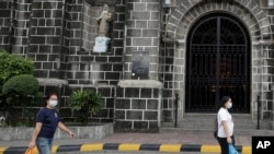 Women wearing protective masks walk in front of a church in Mandaluyong, east of Manila, Philippines on Sunday, Feb. 2, 2020. The Philippines on Sunday reported the first death of a new virus outside of China, where authorities delayed the opening…