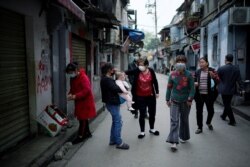 Residents wearing face masks walk at an old residential community blocked by barriers in Wuhan, Hubei province, the epicentre of China's coronavirus disease (COVID-19) outbreak, April 5, 2020.