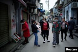 Residents wearing face masks walk in an old residential community blocked by barriers in Wuhan, Hubei province, the epicenter of China's coronavirus outbreak, April 5, 2020.