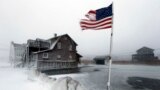 A tattered flag flies by a flooded yard along the shore in Scituate, Massachusetts, Jan. 3, 2014. A blustering winter storm dropped nearly two feet of snow just north of Boston.