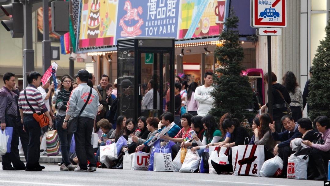 Para turis China beristirahat di pinggir jalan setelah berbelanja di daerah pertokoan mewah Ginza di Tokyo. (Foto: Dok)