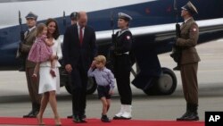 Britain's Kate, the Duchess of Cambridge holding Princess Charlotte, Prince William and Prince George walk past the honor guard, during the arrival ceremony, in Warsaw, July 17, 2017.