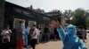 A nurse in a personal protective equipment gestures at the photographer outside a makeshift testing site, after a new outbreak of the coronavirus disease (COVID-19) in Beijing, China June 19, 2020.