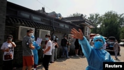 A nurse in a personal protective equipment gestures at the photographer outside a makeshift testing site, after a new outbreak of the coronavirus disease (COVID-19) in Beijing, China June 19, 2020.